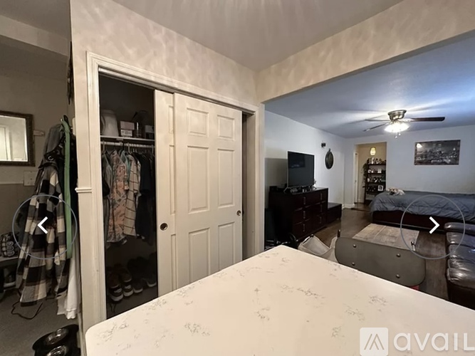 A bedroom with a bed, dresser, and a closet with clothes.