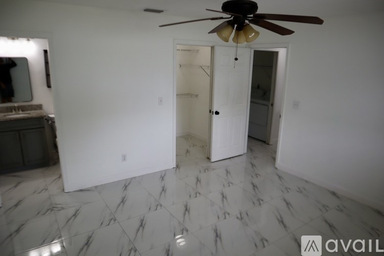 A room with a ceiling fan and marble flooring.