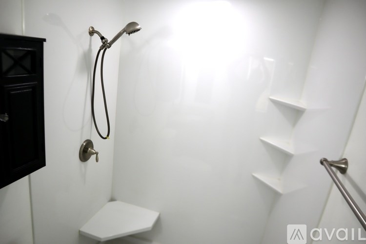 A white toilet is in a small white bathroom with a shower.