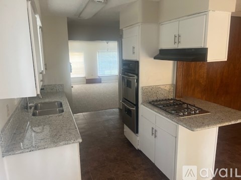 A kitchen with white cabinets and a granite countertop.