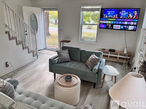 A living room with a grey couch and a flat screen TV mounted on the wall.