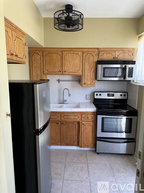 A kitchen with wooden cabinets and a black refrigerator.