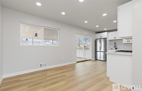 A spacious kitchen with white cabinets and a stainless steel refrigerator.