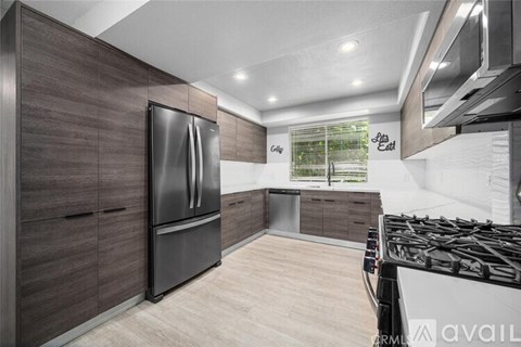 A modern kitchen with dark wood cabinets and a stainless steel refrigerator.