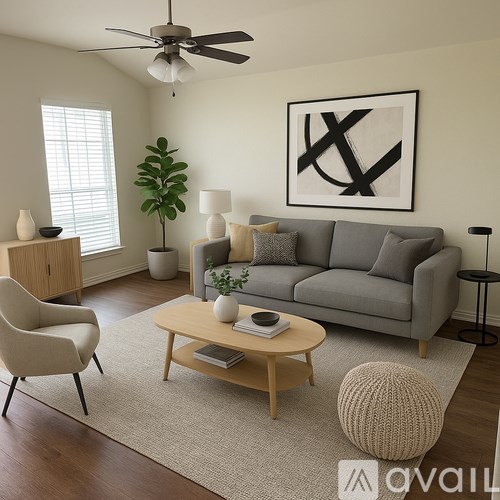 A living room with a grey couch, a wooden coffee table, a white chair, a green plant, and a black and white abstract painting on the wall.