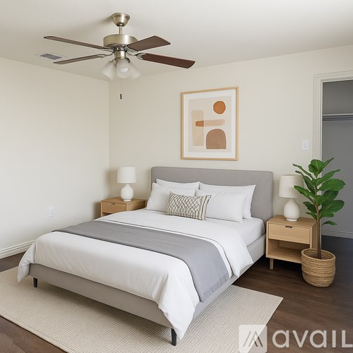 A bedroom with a bed, nightstands, a ceiling fan, and a plant.