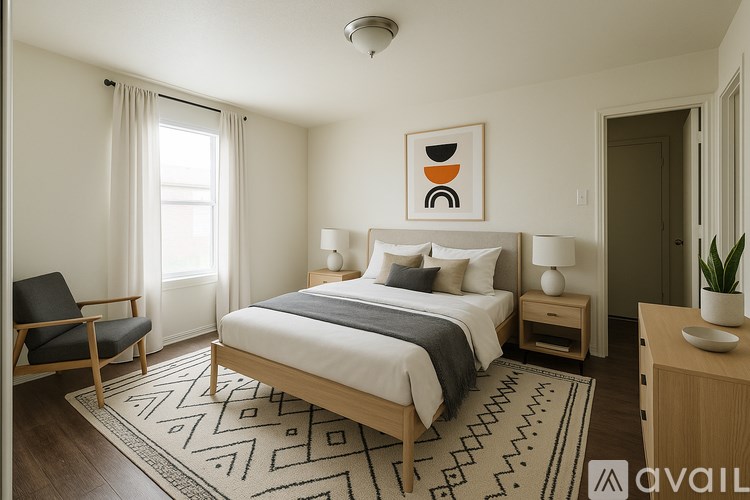 A well-lit bedroom with a large bed, a chair, and a side table.