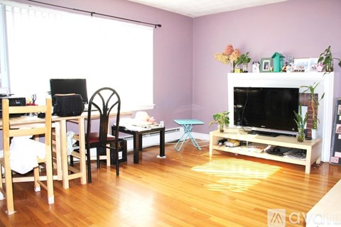 A living room with a wooden floor and a purple wall.