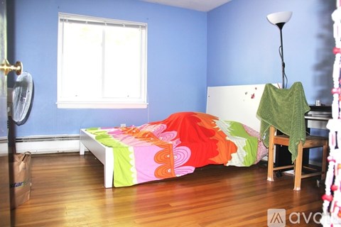 A bedroom with a bed covered in a colorful comforter.