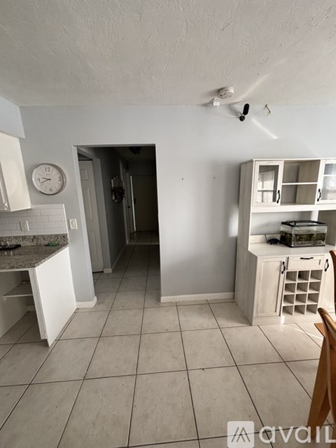 A kitchen with white cabinets and a clock on the wall.