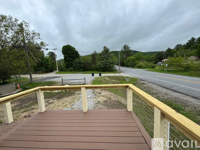 A wooden deck overlooks a road with a cloudy sky above.