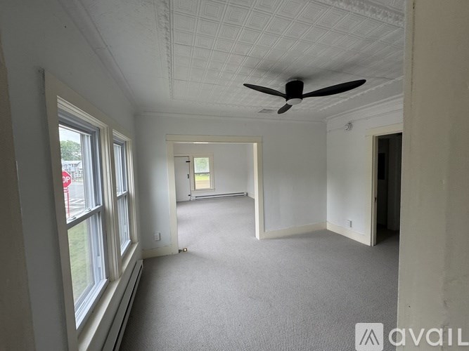A room with a ceiling fan and carpeted floor.