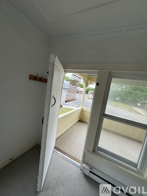 A room with a white door and a window with a view of a street.