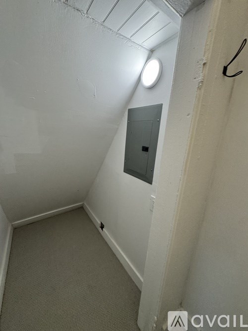 A small, white room with a round light on the ceiling and a door on the right.