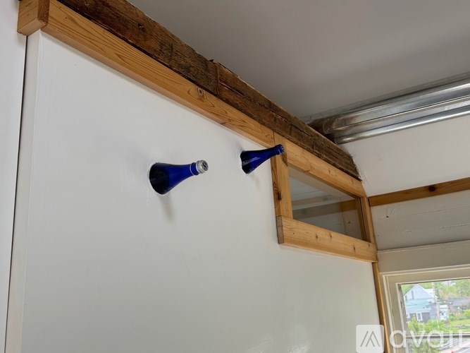 A white refrigerator with a wooden frame and two blue bottles on top.