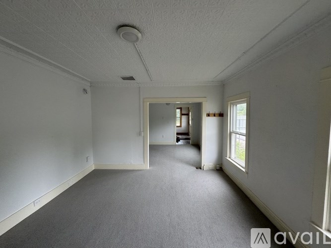 A spacious room with a carpeted floor and white walls.