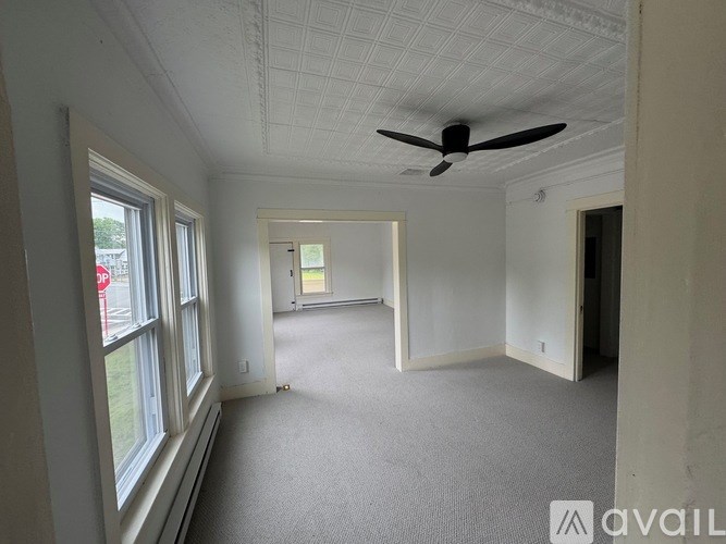 A room with a ceiling fan and carpeted floor.