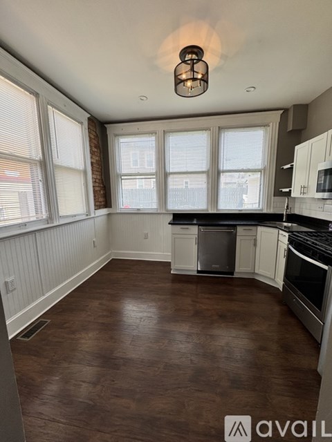 A kitchen with white cabinets and a brown floor.