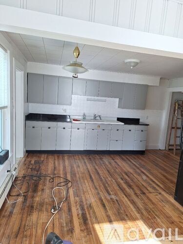 A kitchen with wooden floors and white cabinets is under renovation.