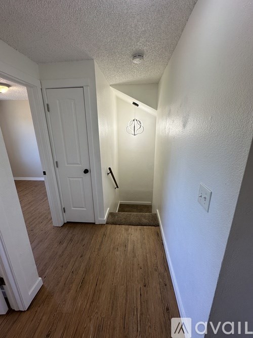 A hallway with a white door and wooden floors.