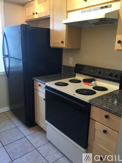 A kitchen with black appliances and wooden cabinets.
