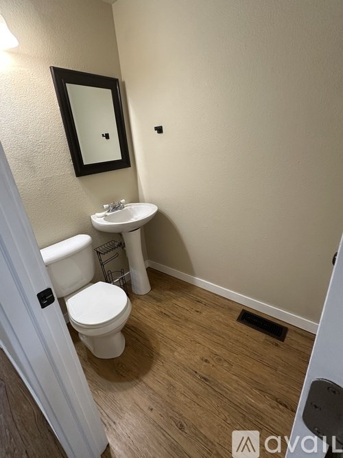 A bathroom with a toilet, sink, and mirror.