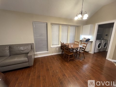 A living room with a grey couch and a wooden dining table.