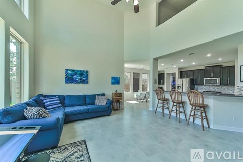A living room with a blue couch and a kitchen in the background.