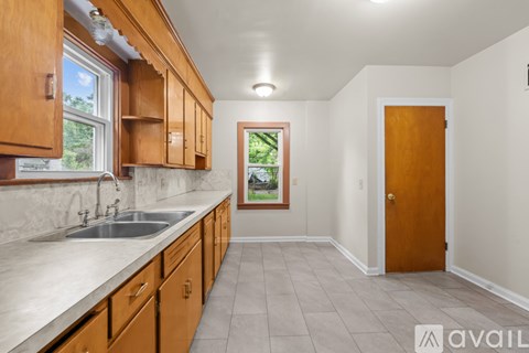 A kitchen with wooden cabinets and a window overlooking a green landscape.