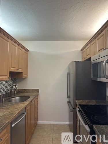 A kitchen with wooden cabinets and a black fridge.