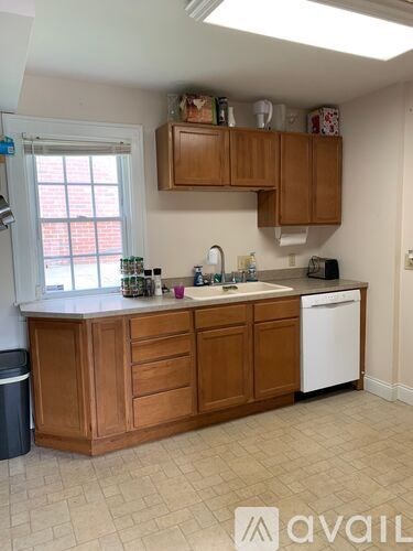 A kitchen with wooden cabinets and a white dishwasher.