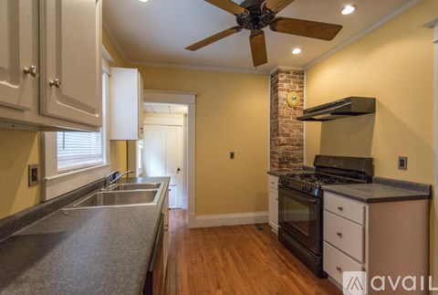 A kitchen with a brick wall and a ceiling fan.