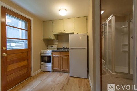 A kitchen with a white fridge and wooden floors.