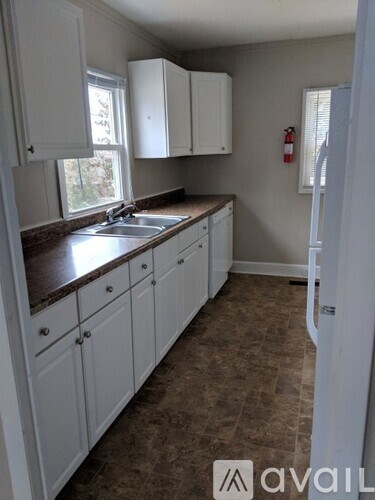 A kitchen with white cabinets and brown countertops.