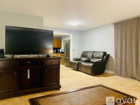 A living room with a black leather sofa and a wooden cabinet.
