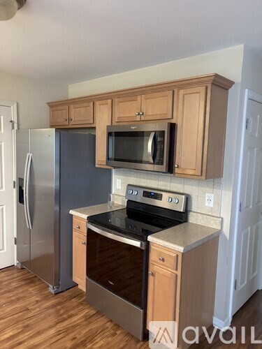 A kitchen with wooden cabinets and a stainless steel refrigerator.