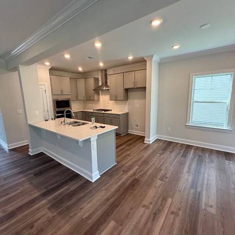 A kitchen with a white island and wooden floors.
