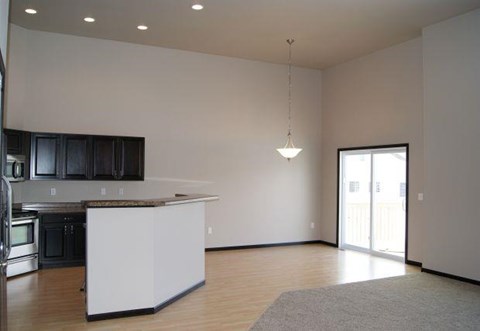 an empty living room with a kitchen and a door