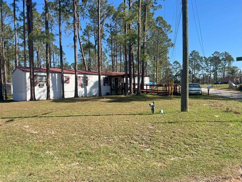 A grassy area with a building and trees in the background.