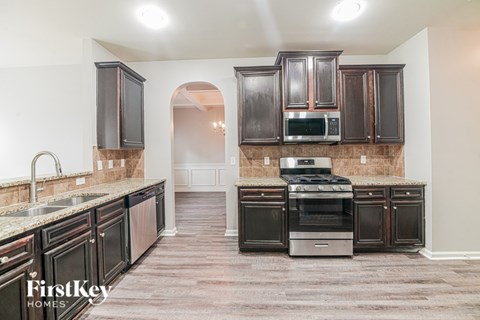 A kitchen with dark wood cabinets and a stainless steel oven.