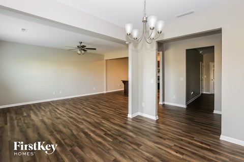 A spacious room with wooden floors and a ceiling fan.
