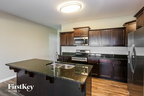 A kitchen with a black counter top and wooden cabinets.
