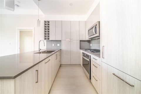 A modern kitchen with white cabinets and a black countertop.