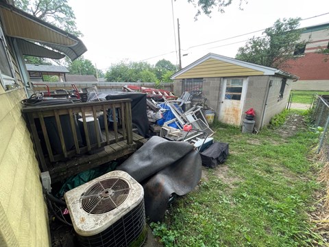 A cluttered yard with a shed and a fan.