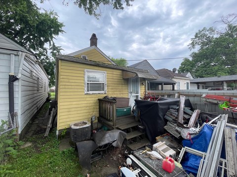 A yellow house with a lot of junk in front of it.