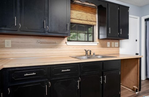 A kitchen with black cabinets and a wooden countertop.