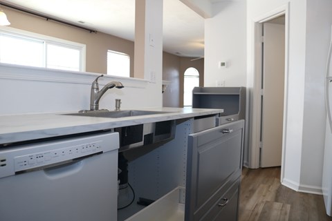 A kitchen with a white sink and grey cabinets.