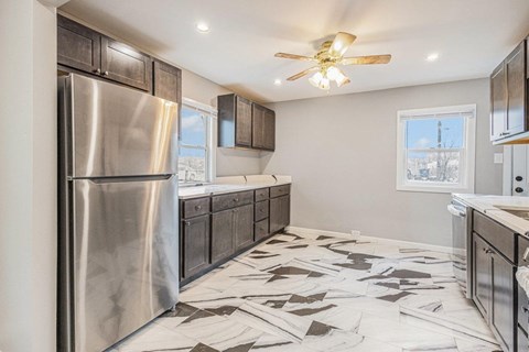 A modern kitchen with a stainless steel refrigerator and a ceiling fan.