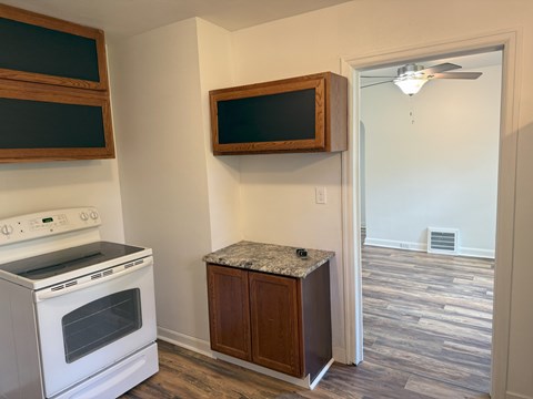 A kitchen with a white stove and a wooden cabinet.
