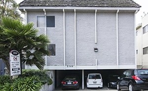 A grey house with a white car parked in front.